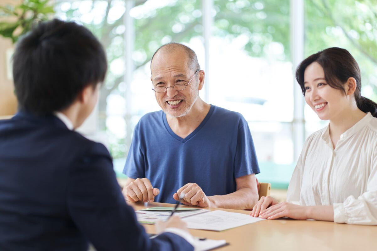 Smiling senior man and woman meeting with a Medicare independent agent, discussing personalized health plan options in a bright and welcoming office setting.